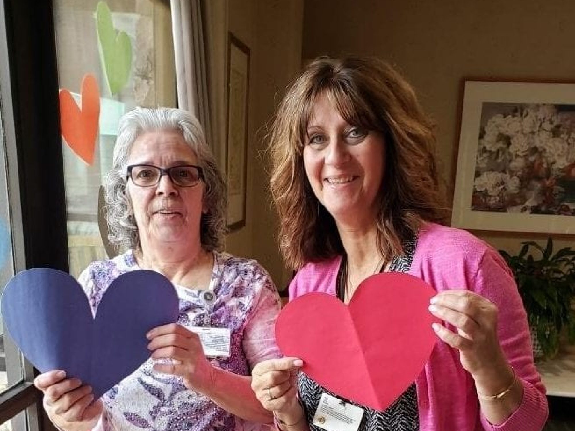 Two women holding paper heart cut outs