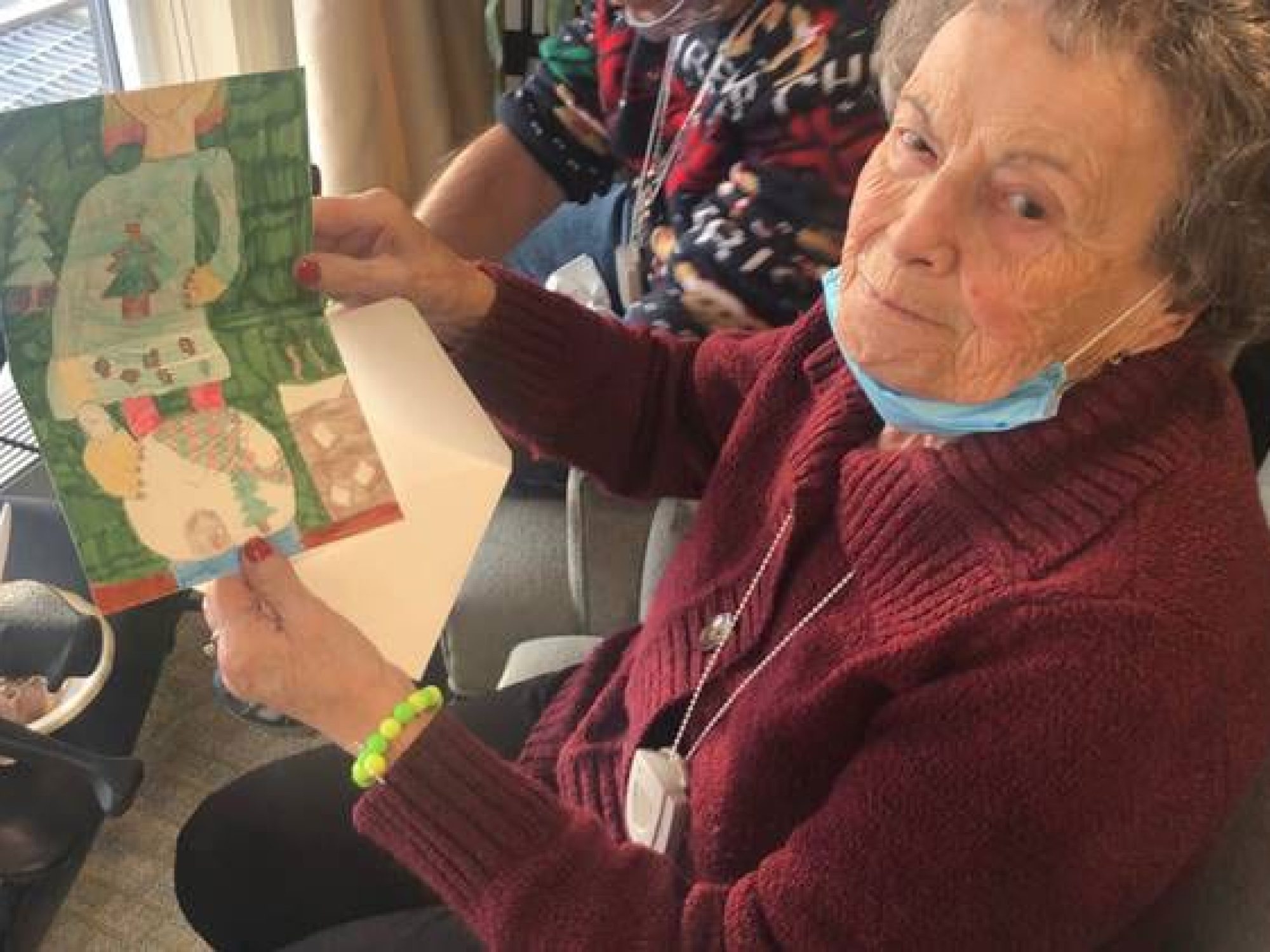 A resident of Ruth's House holding a holiday card and looking at the camera