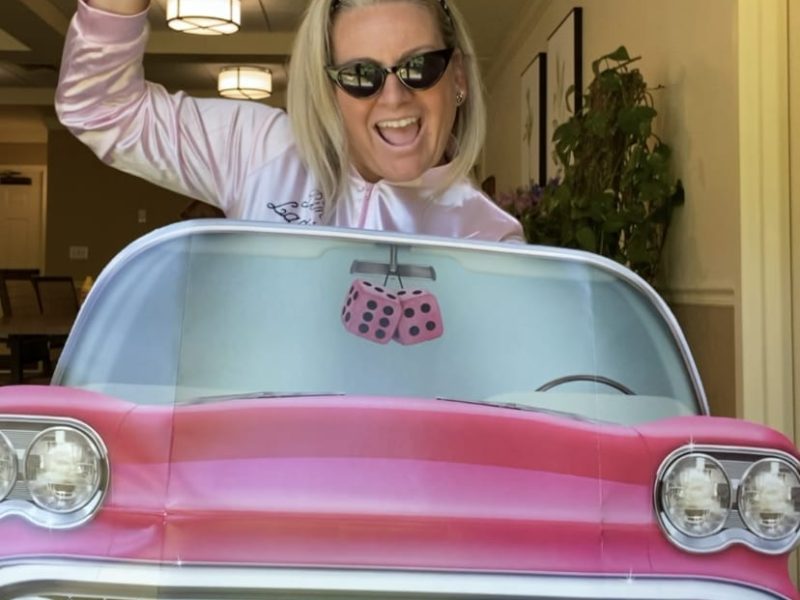 Andrea from Ruth's House in Longmeadow, Massachusetts poses in a cardboard cut out of a pink 50s car.