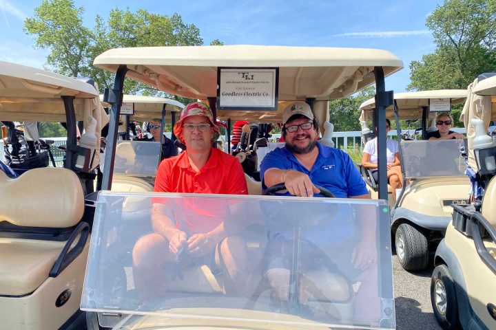 Two golfers in their golf cart at the Frankel Kinsler Golf Tournament