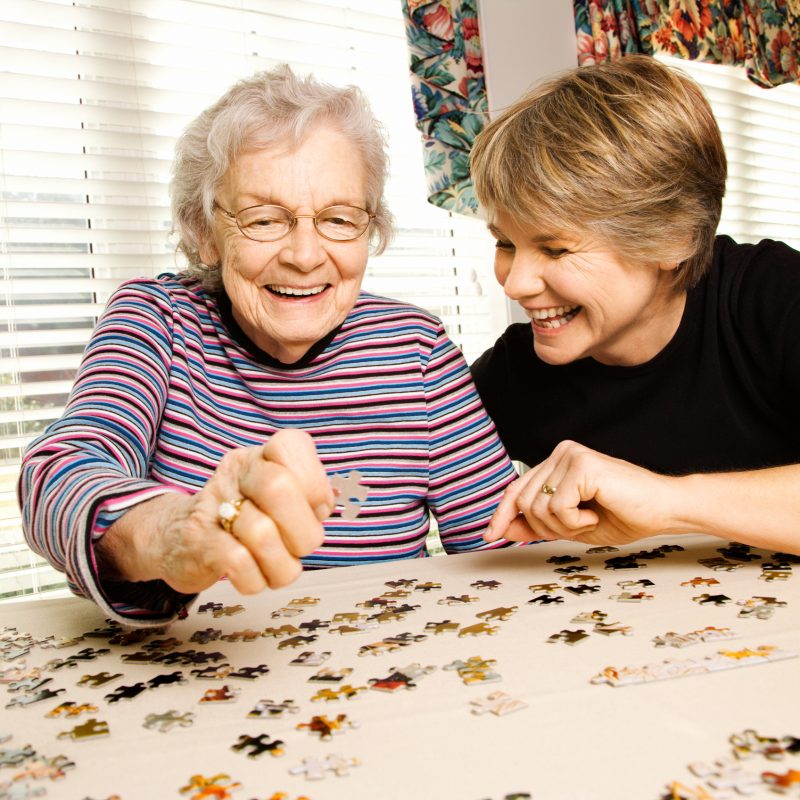 Two older women happily putting together a puzzle