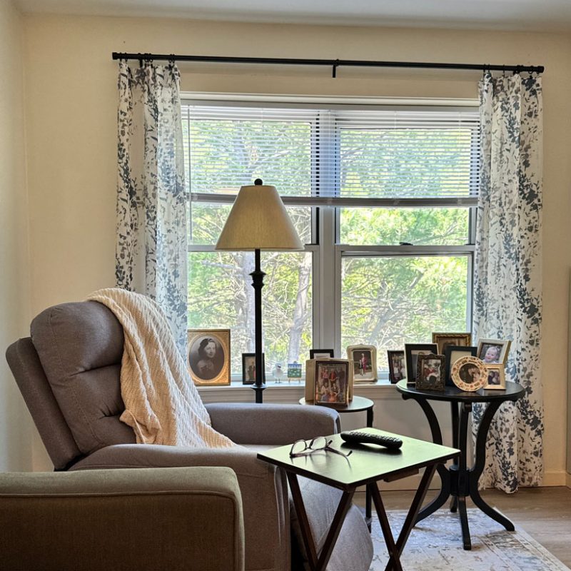 Living room interior with a chair, some tables and family portraits in frames.
